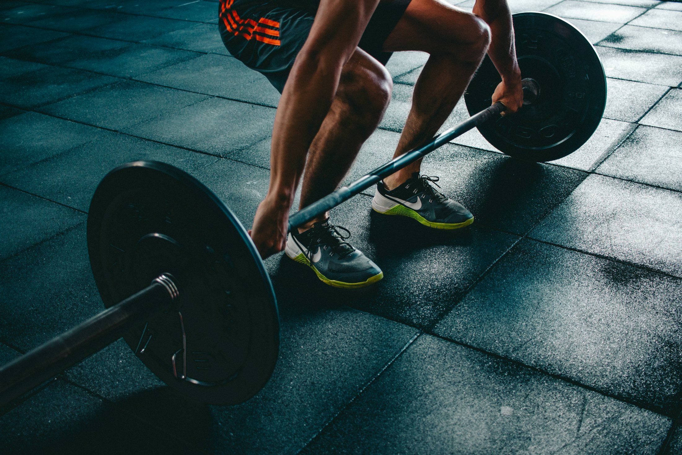 Close-up of an athlete gripping a loaded barbell on a gym floor